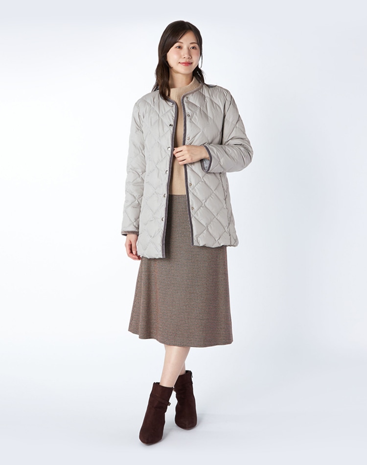 グレーのタフタコートとチェックスカートを身に着けた女性