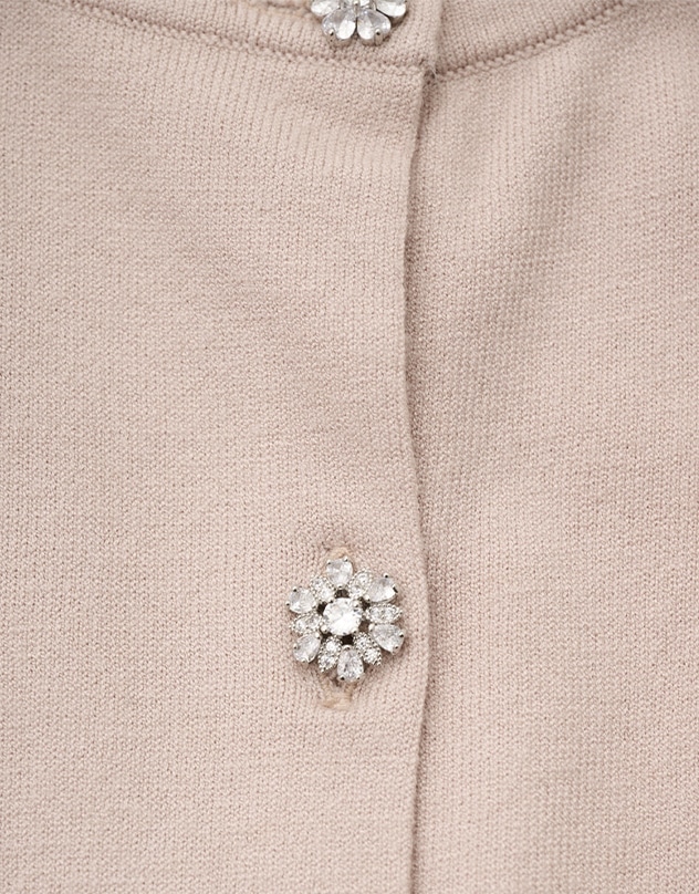 グレイッシュピンクのカーディガンの、ビジューボタンをアップで撮影した写真