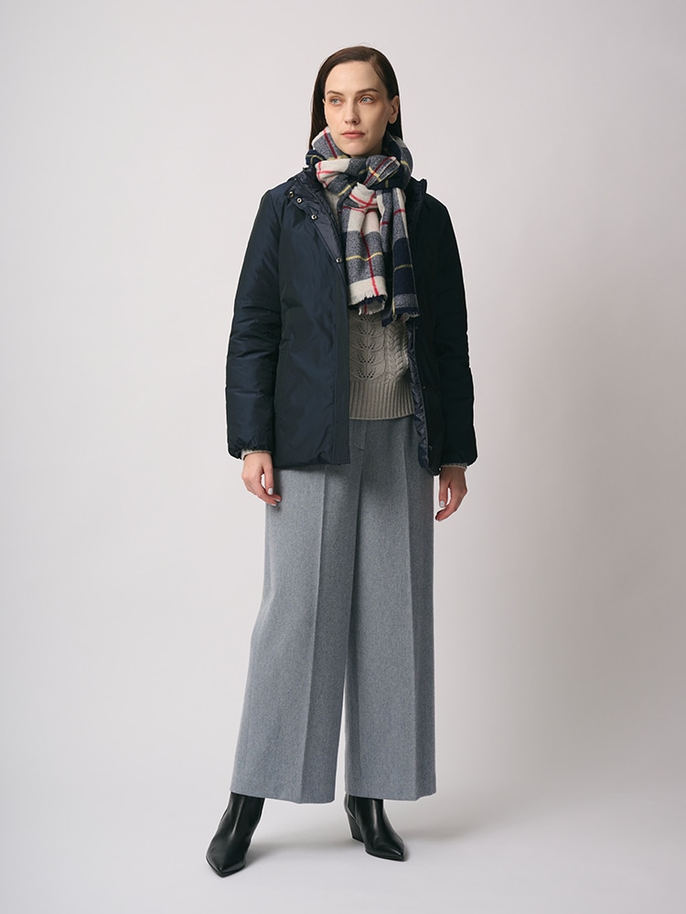 ネイビーのリバーシブルダウンコート、グレーのパンツ、チェックのマフラーを身に着けた女性