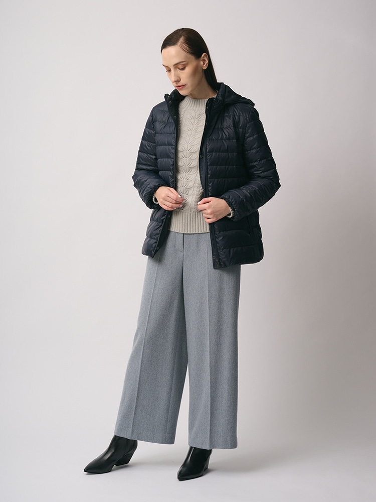 ネイビーのリバーシブルダウンコート、グレーのパンツを身に着けた女性