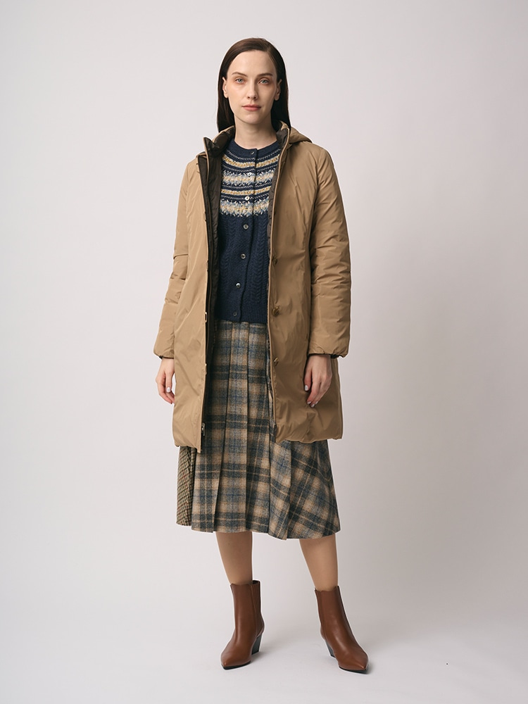 ベージュのリバーシブルダウンコート、チェックのスカートを身に着けた女性