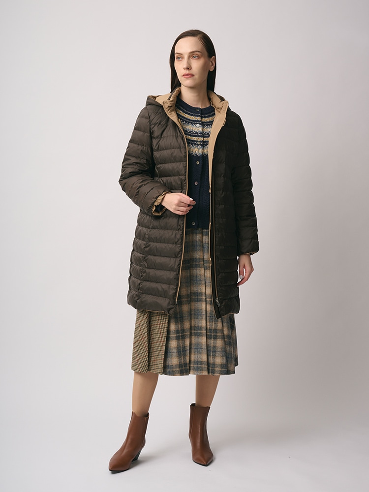 ブラウンのリバーシブルダウンコート、チェックのスカートを身に着けた女性