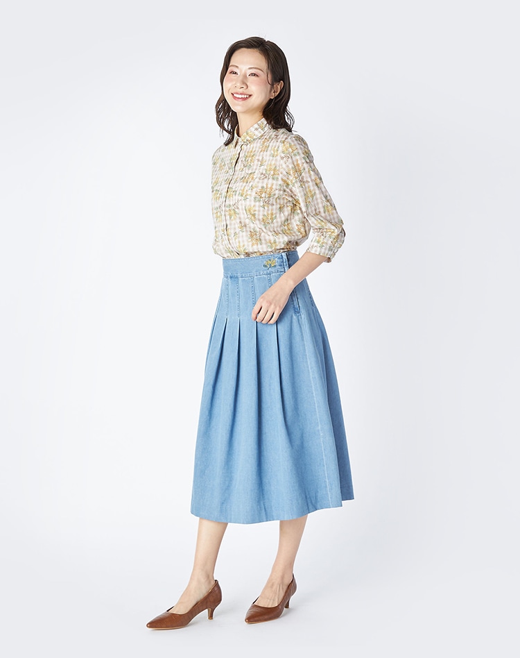 イエローの花柄のシャツとデニムスカートを身に着けた女性