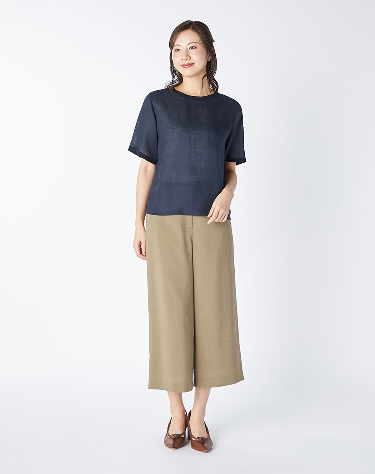 ネイビーのプルオーバーとベージュのワイドパンツを身に着けた女性