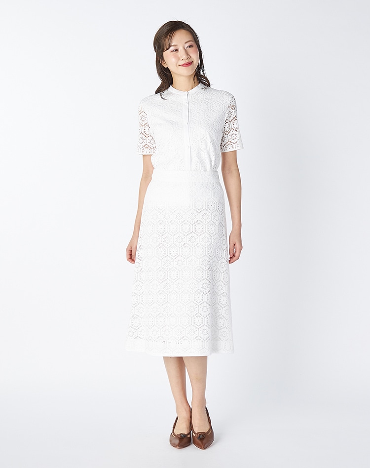 ホワイトのレースカットソーとホワイトのレーススカートを身に着けた女性