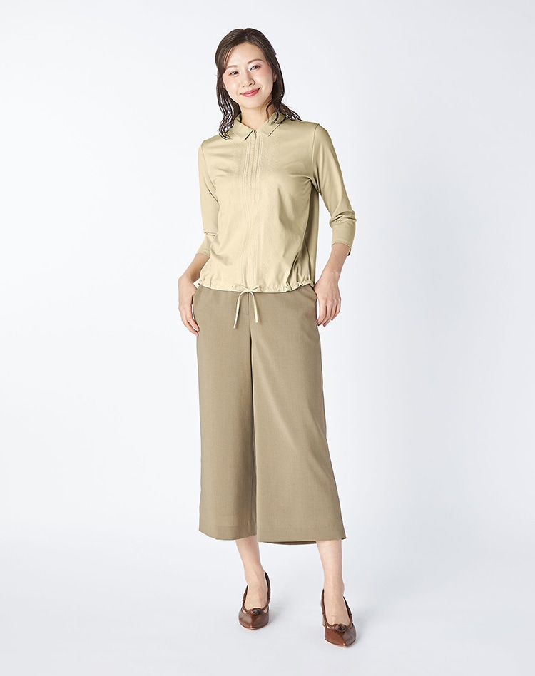 ベージュのシャツとベージュのワイドパンツを身に着けた女性