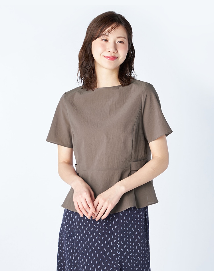 ブラウンのブラウスとネイビーのペイズリー柄スカートを身に着けた女性