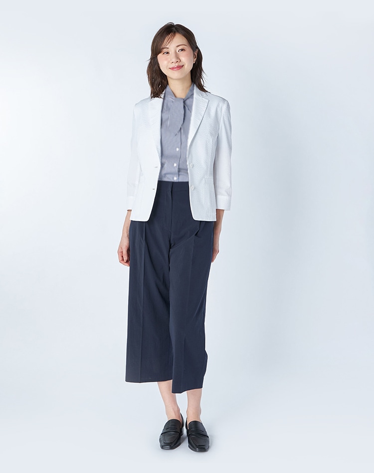 白のジャケットとストライプ柄のブラウスを身に着けた女性