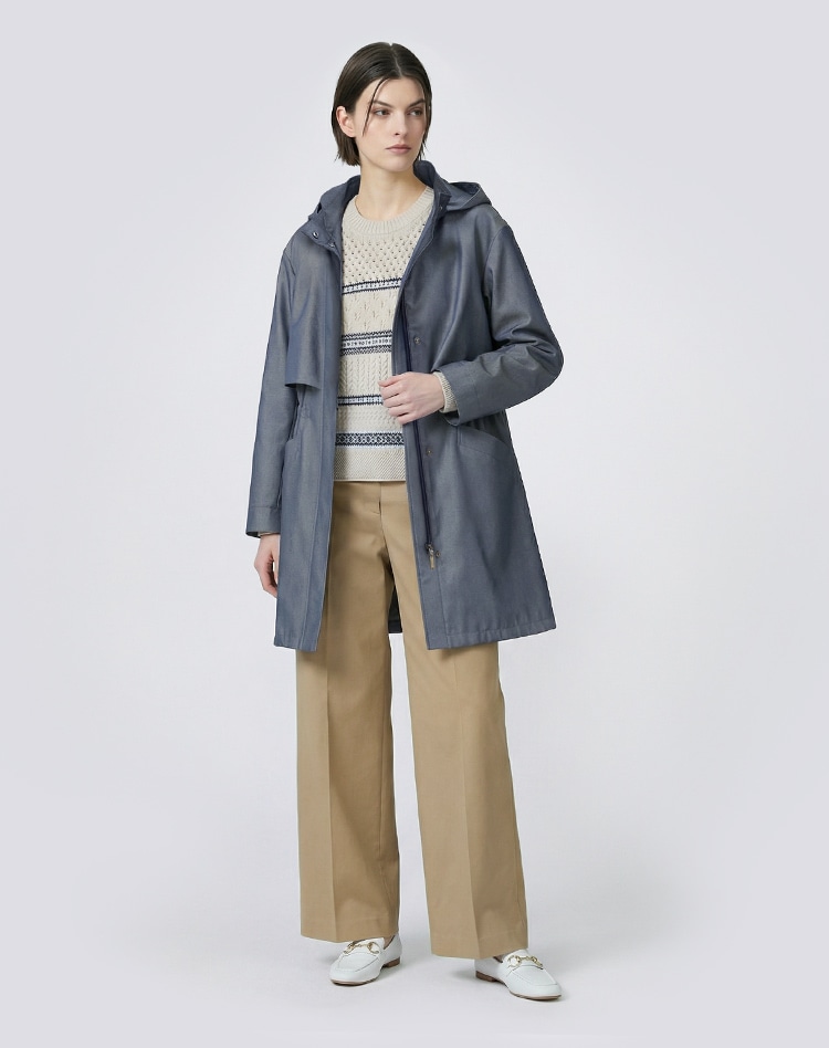 ダークブルーのコートとベージュのチノパンツを身に着けた女性