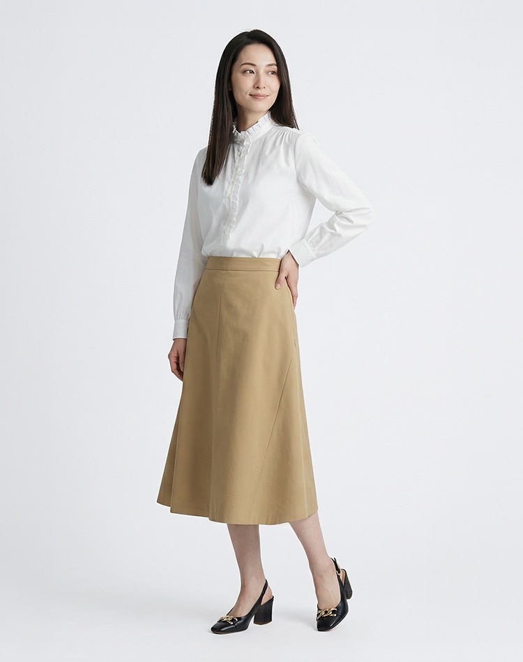ホワイトのブラウスとベージュのスカートを身に着けた女性