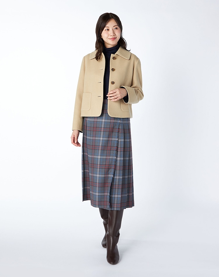 ベージュのジャケットとチェックスカートを身に着けた女性