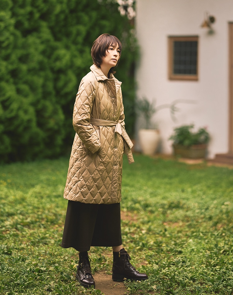 ベージュのダウンコート、ダークブラウンのパンツを身に着けた女性