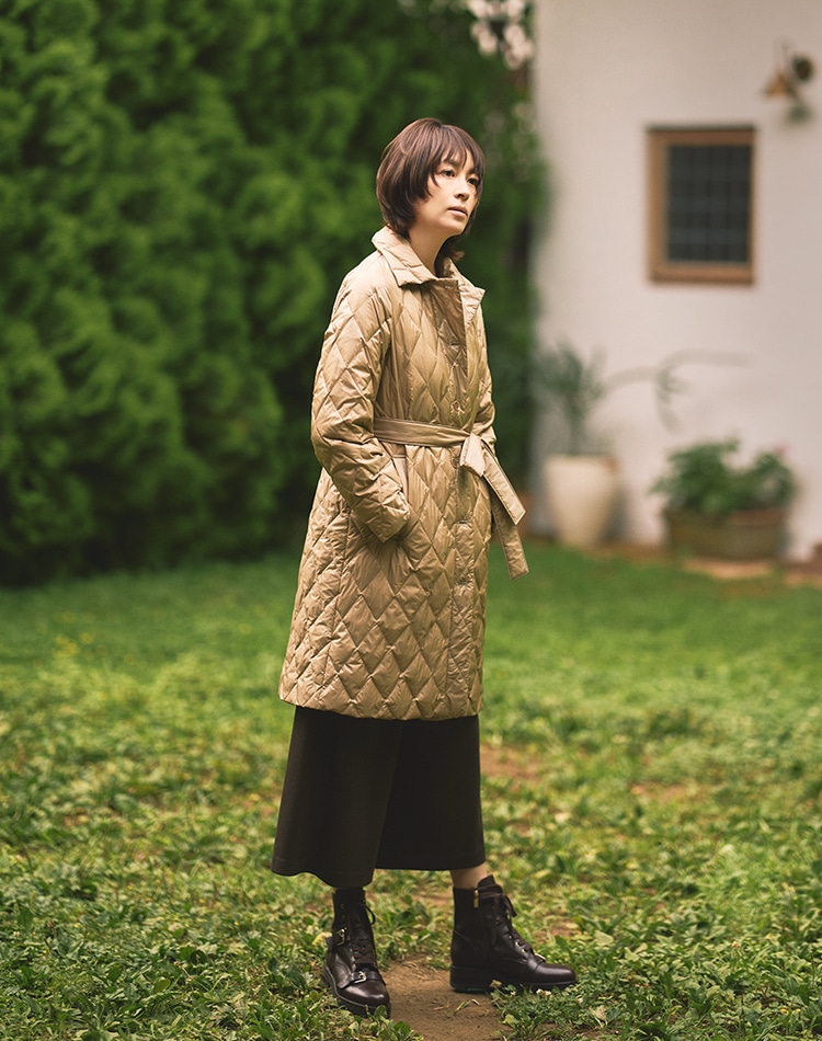 ベージュのダウンコート、ダークブラウンのパンツを身に着けた女性