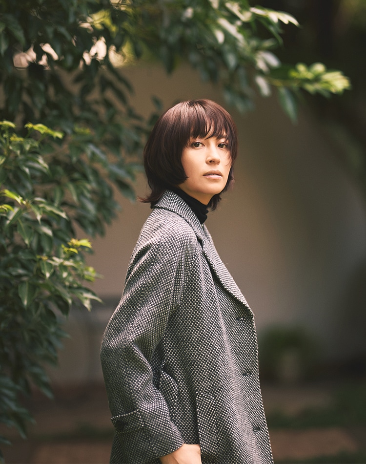 グレーのコート、ブラックのニットを身に着けた女性