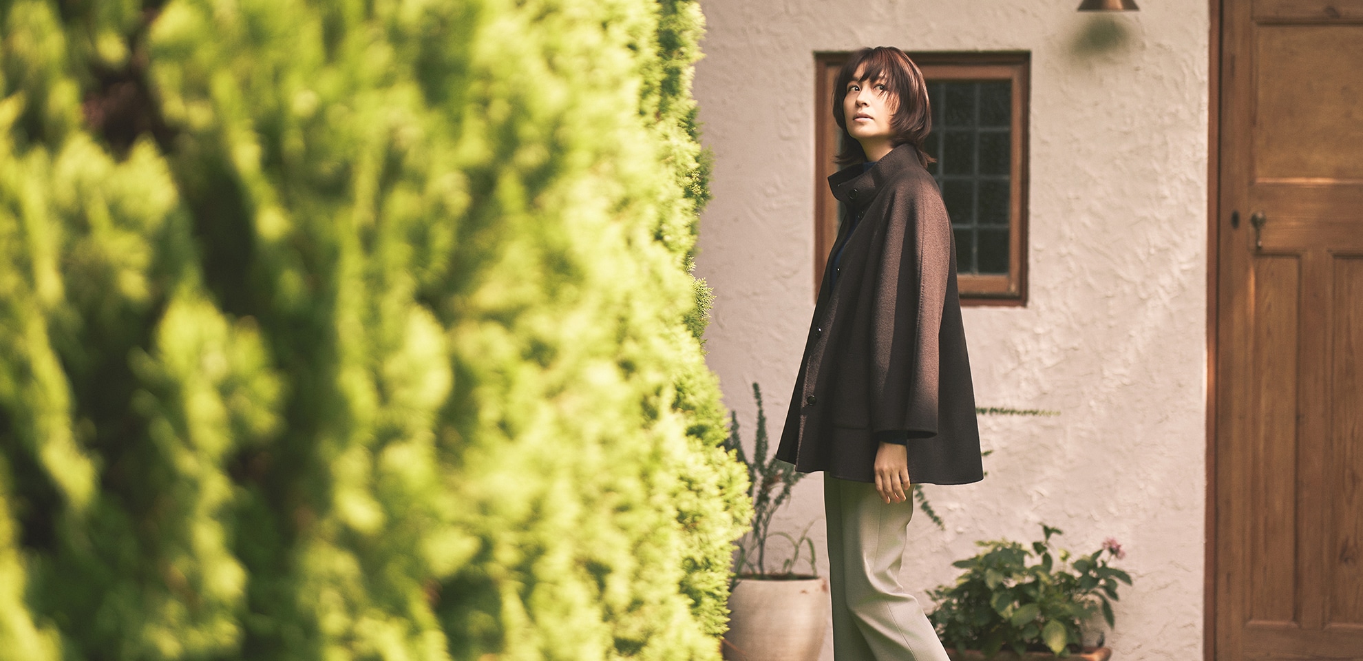 ダークブラウンのコート、グレーのパンツを身に着けた女性