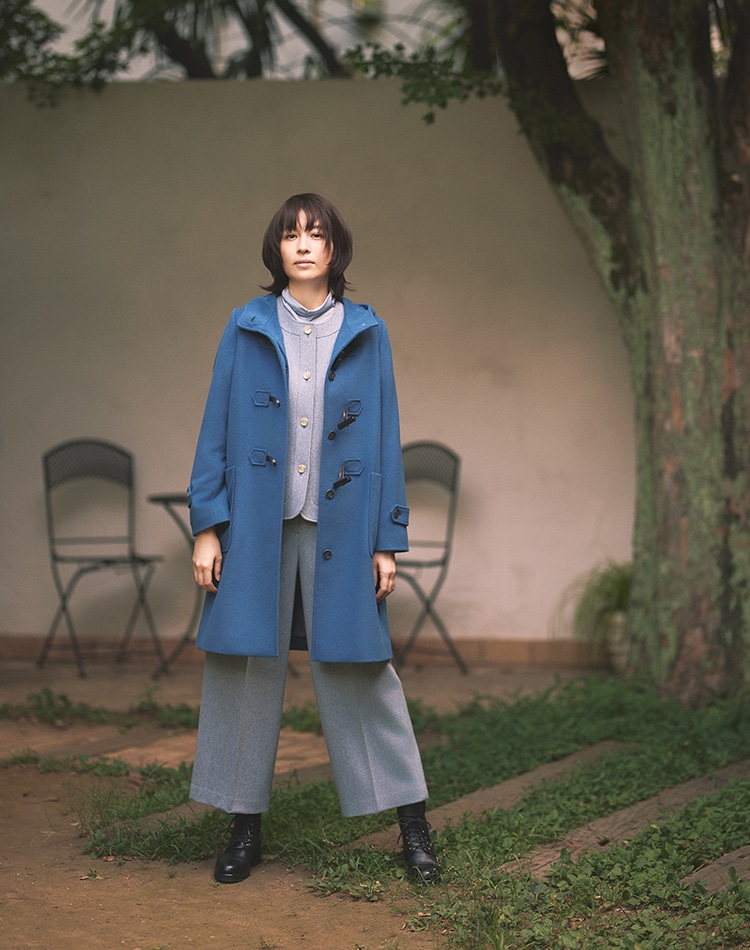 ブルーのコート、ブルーのジャケット、ブルーのパンツを身に着けた女性