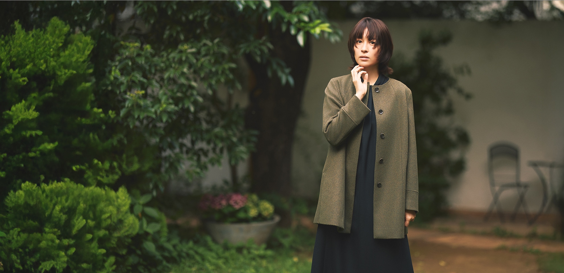 モスグリーンのコート、ブラックのワンピースを身に着けた女性