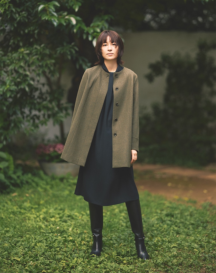 モスグリーンのコート、ブラックのワンピースを身に着けた女性