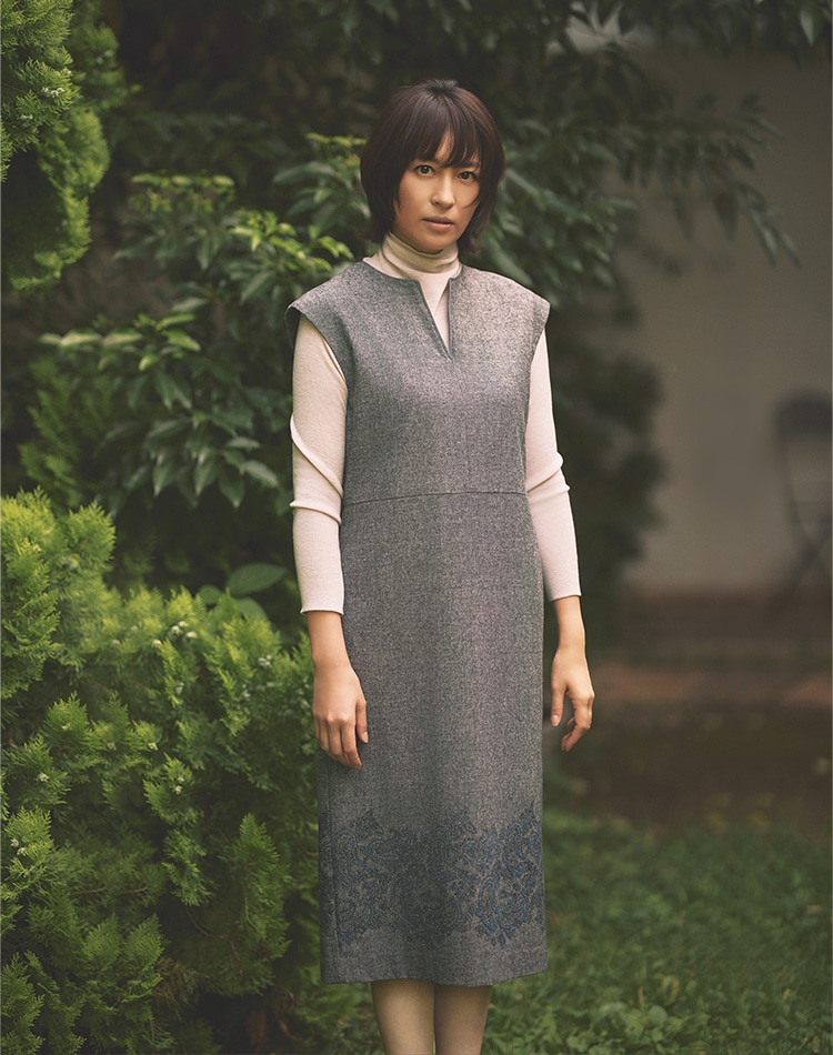 グレーのワンピース、ホワイトのカットソーを身に着けた女性