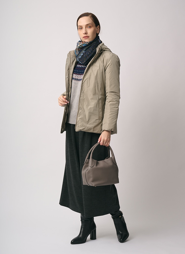 ベージュのダウンコート、ブルーのスカーフ、グレーのフェアアイル柄のニット、チャコールグレーのパンツを身に着けた女性