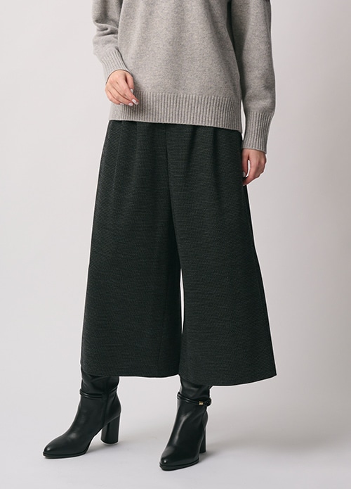 グレーのフェアアイル柄のニット、チャコールグレーのパンツを身に着けた女性