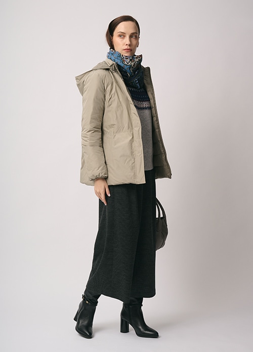 ベージュのダウンコート、ブルーのスカーフ、グレーのフェアアイル柄のニット、チャコールグレーのパンツを身に着けた女性