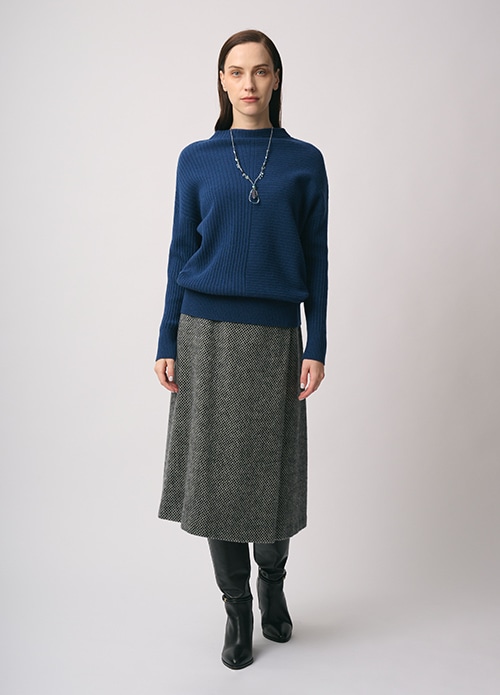 ブルーのニット、グレーのスカートを身に着けた女性