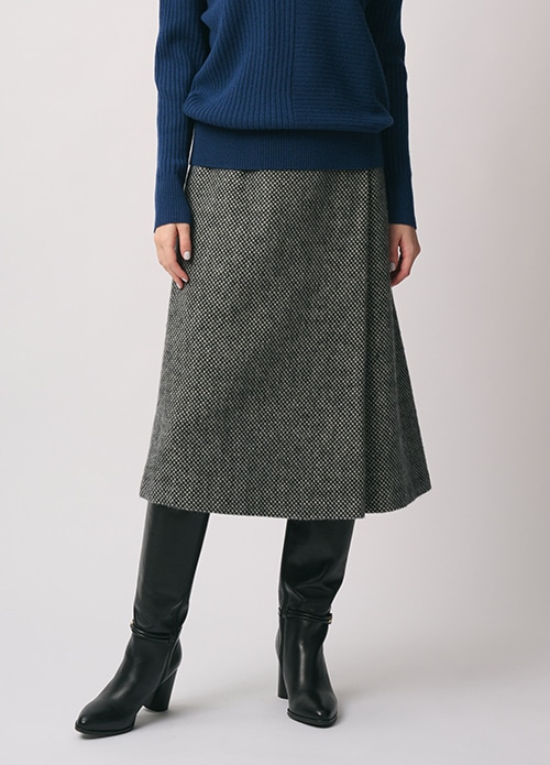 ブルーのニット、グレーのスカートを身に着けた女性