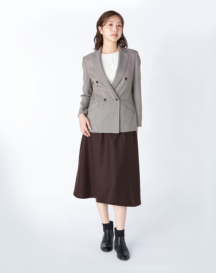 ダークブラウンチェック柄のジャケットとダークブラウンのスカートを身に纏った女性