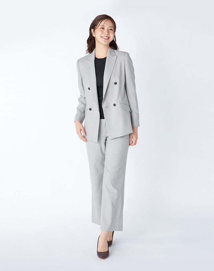 グレーチェック柄のジャケットとパンツのセットアップを身に纏った女性