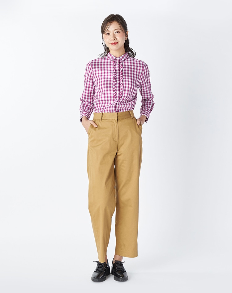 パープルのギンガムブラウスとブラウンのパンツを身に着けた女性