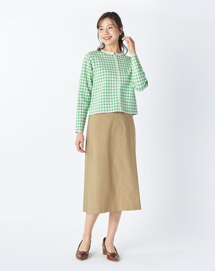 グリーンのチェックカーディガンとベージュのスカートを身に着けた女性