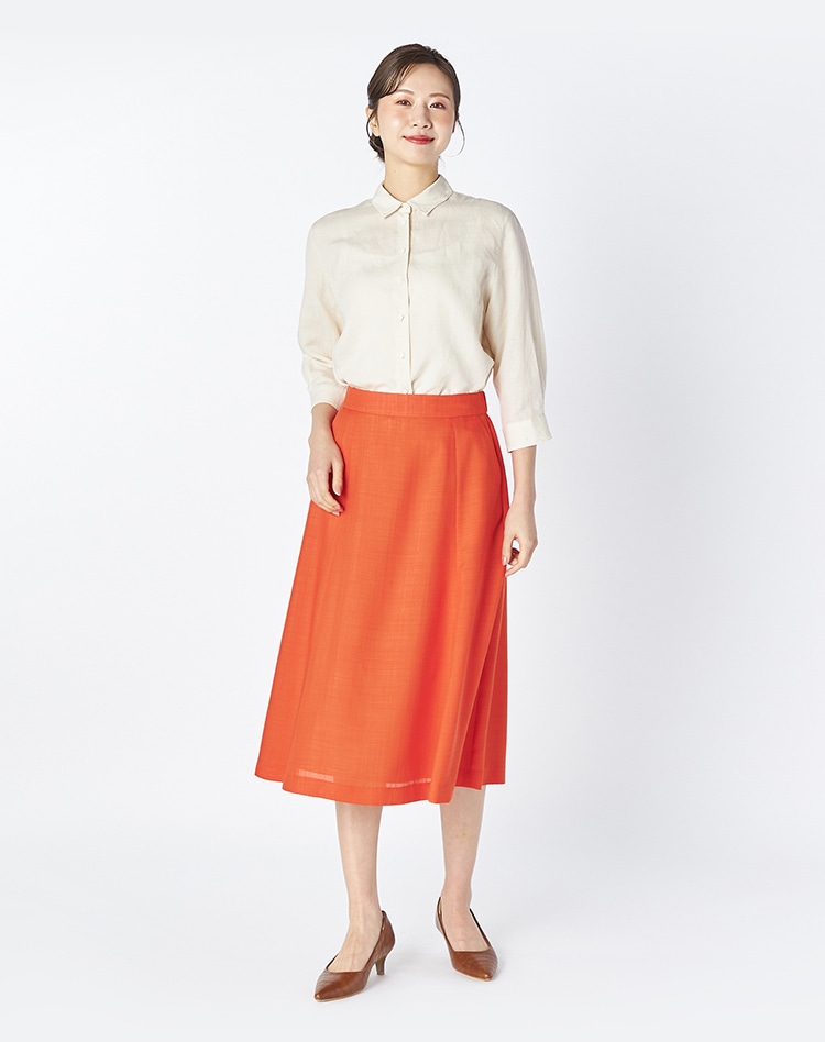 ホワイトのブラウスとオレンジのスカートを身に着けた女性