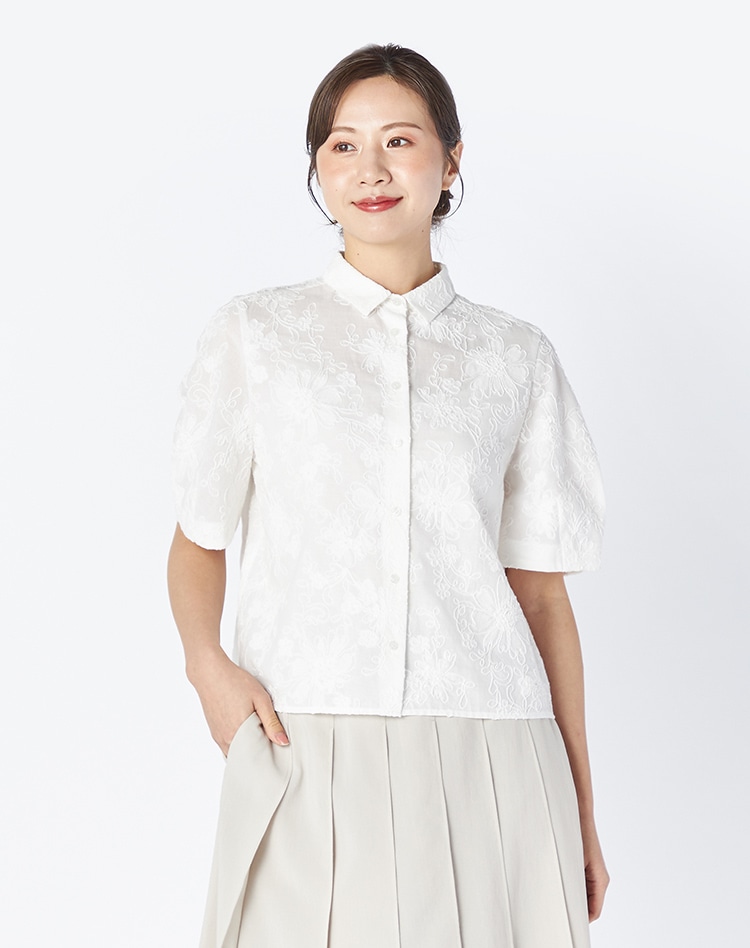 ホワイトのレースのブラウスとホワイトのスカートを身に着けた女性