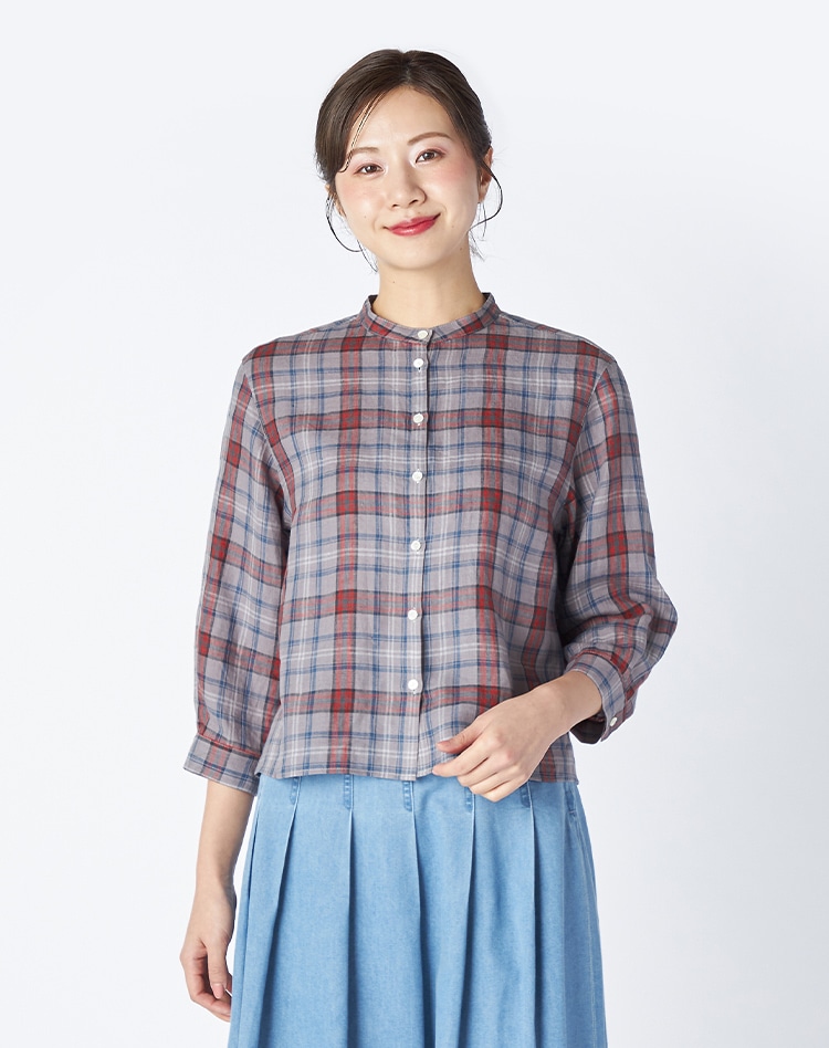 グレーのチェックのブラウスとライトブルーのスカートを身に着けた女性