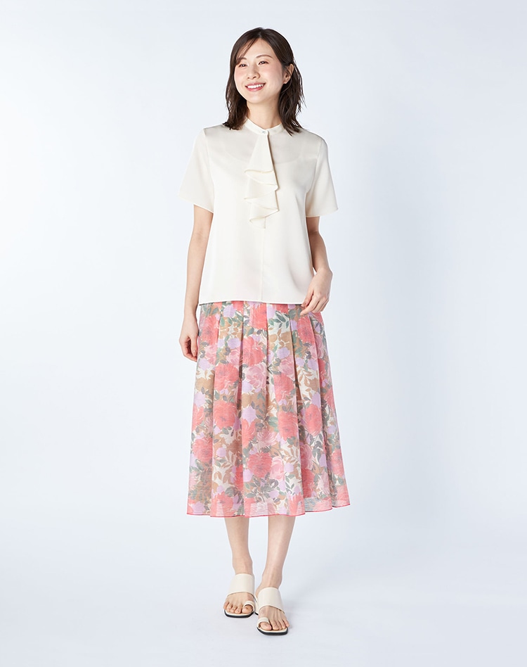 ホワイトのブラウスとレッドのフラワー柄のスカートを身に着けた女性