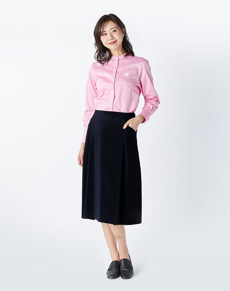 ピンクのブラウスとブラックのコーデュロイスカートを身に着けた女性