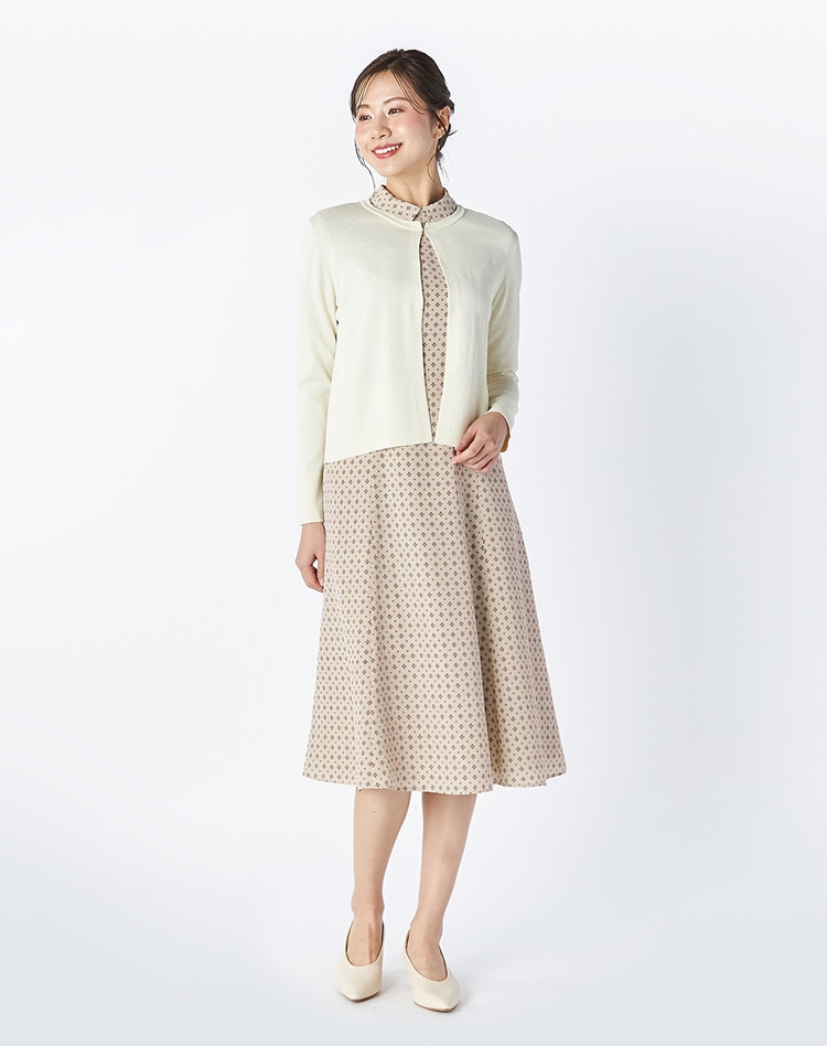 ホワイトのニットとベージュの総柄のワンピースを身に着けた女性