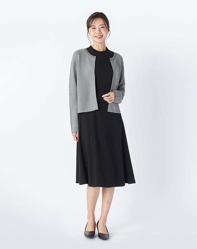 グレーのニットとブラックのワンピースを身に着けた女性