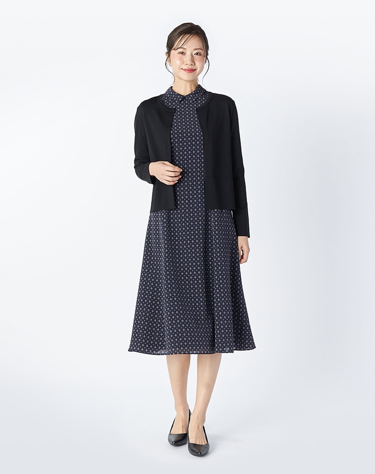 ブラックのニットとネイビーの総柄のワンピースを身に着けた女性