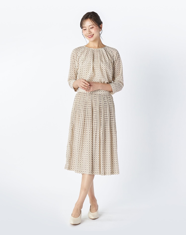 ベージュの総柄のセットアップを身に着けた女性