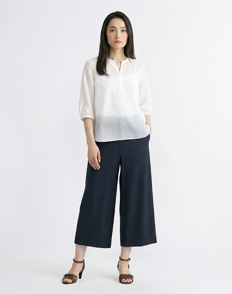 ホワイトのブラウスとネイビーのワイドパンツを身に着けた女性