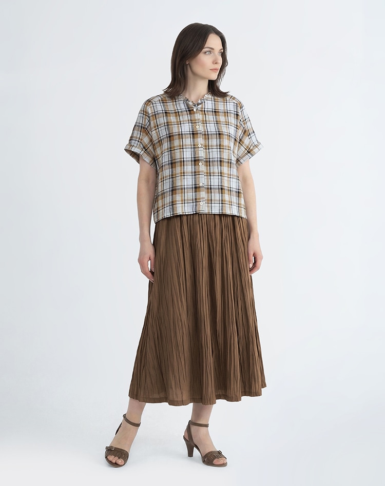 チェック柄のブラウスとブラウンのスカートを身に着けた女性