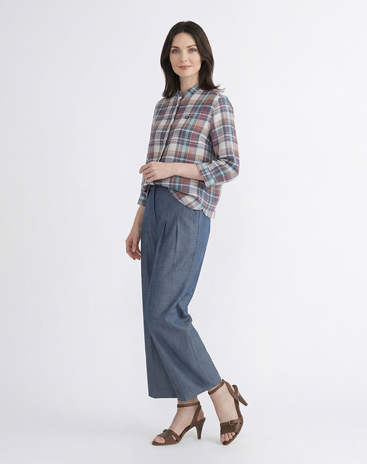 チェック柄のブラウスとブルーのパンツを身に着けた女性