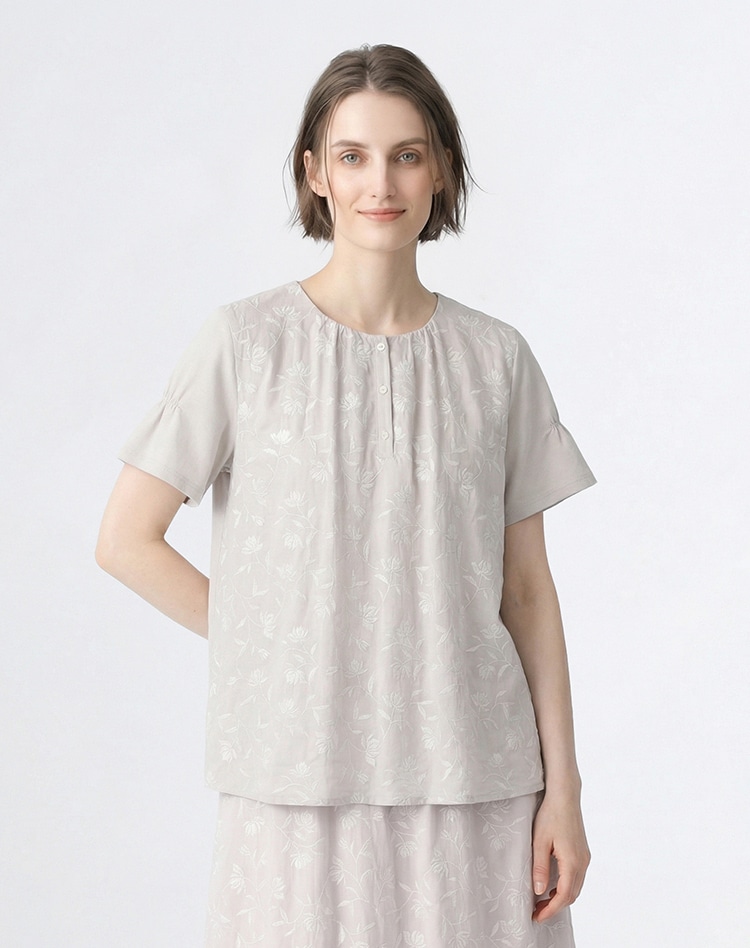 グレーのフラワー柄のブラウスを身に着けた女性