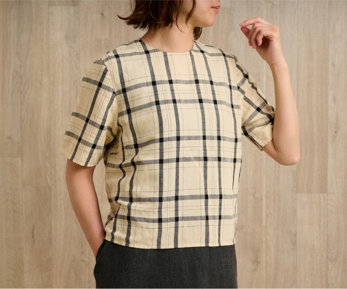 ベージュとブラックのチェック柄ブラウスを着た女性