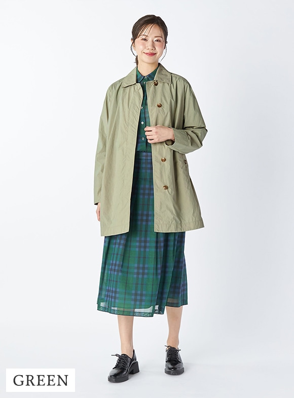 グリーンのコートとチェックのセットアップを身に着けた女性