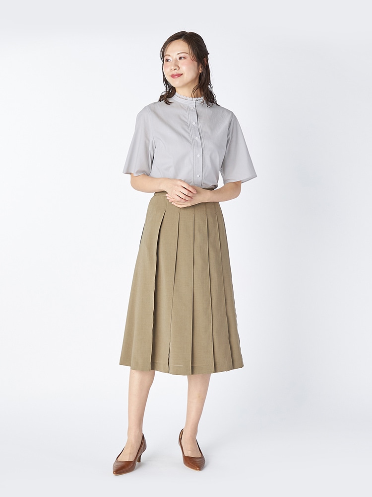 グレーのブラウスとグリーンのスカートを着た女性