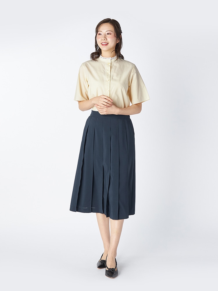 イエローのブラウスとネイビーのスカートを着た女性