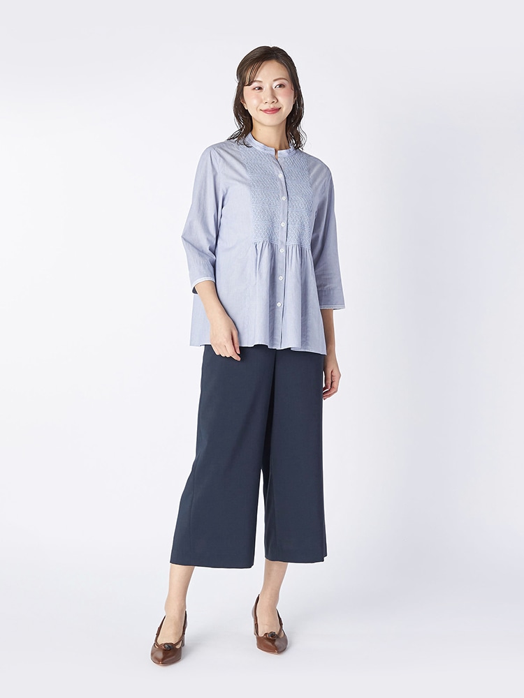 ブルーのブラウスとネイビーのパンツを着た女性